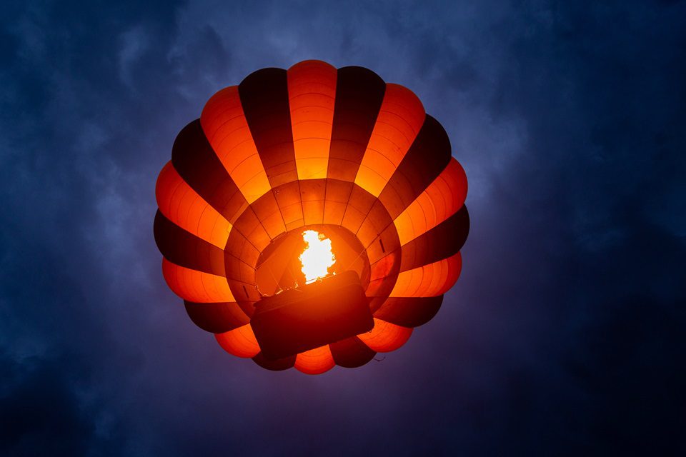 Hot air balloon floating over the Serengeti at sunrise with wildlife below